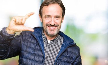 Orta yaş yakışıklı adam kış ceket giymiş ve el ile kamera ve görünümlü iken parmaklar ile boyut işareti yapan emin işaret. Ölçü kavramı.