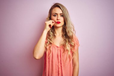 Pembe izole edilmiş arka plan ağzının üzerinde duran tişört giyen genç ve güzel bir kadın ve parmaklarıyla fermuar gibi kapanan dudaklar. Gizli ve sessiz, tabu konuşması