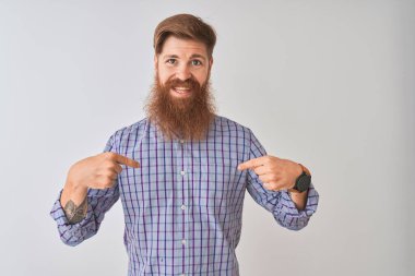 Genç kızıl saçlı İrlandalı adam izole beyaz arka plan üzerinde duran rahat gömlek giyen yüzünde gülümseme ile emin görünümlü, parmakları gururlu ve mutlu kendini işaret.