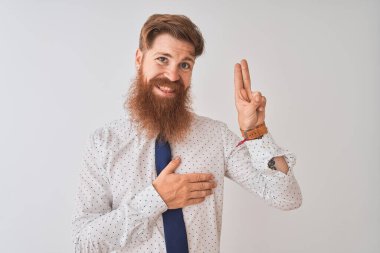 Young redhead irish businessman standing over isolated white background smiling swearing with hand on chest and fingers up, making a loyalty promise oath clipart