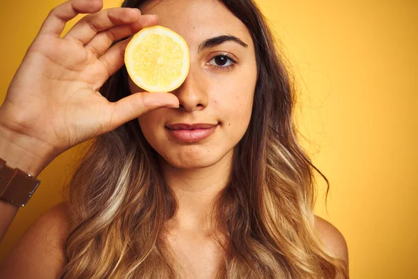 Joven Mujer Hermosa Sosteniendo Limón Ojo Sobre Fondo Aislado Amarillo —  Fotos de Stock
