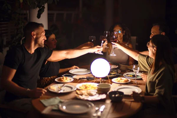 Beautiful family toasting with cup of wine on dinner smiling at terrace