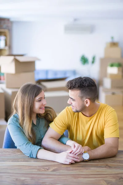 Joven hermosa pareja sentada en la mesa en casa, abrazándose — Foto de Stock