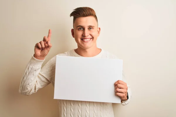 Jovem Homem Bonito Segurando Banner Sobre Fundo Branco Isolado Surpreso — Fotografia de Stock