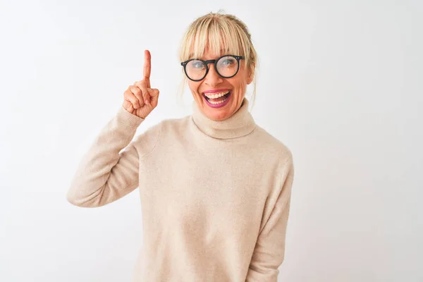 成功したアイデアで指を指して隔離された白い背景の上に亀甲セーターと眼鏡を身に着けている中年の女性 興奮し 第一番 — ストック写真