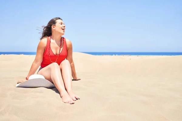 年轻美丽的女人穿着夏装坐在沙滩上晒日光浴在睫毛膏沙丘上 — 图库照片