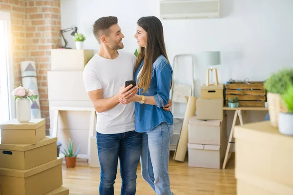 Jong stel verhuizen naar een nieuw huis, met behulp van smartphone lachend ver — Stockfoto