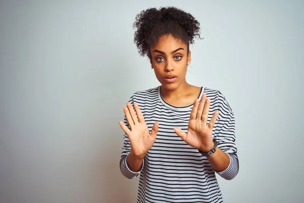 African american woman wearing navy striped t-shirt standing over isolated white background Moving away hands palms showing refusal and denial with afraid and disgusting expression. Stop and forbidden.