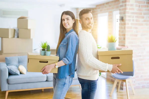 Pareja joven mudándose a un nuevo hogar, sonriendo feliz sosteniendo cardboa —  Fotos de Stock