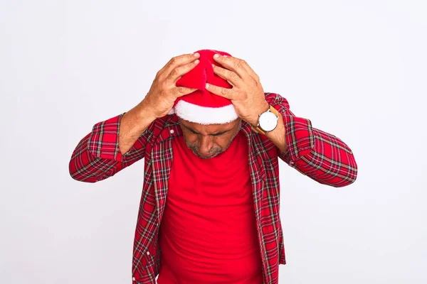 痛みや片頭痛のために必死に頭痛やストレスに苦しんで隔離された白い背景の上に立ってクリスマスサンタの帽子を身に着けている中世の男 手を頭に — ストック写真