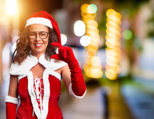 中年妇女身穿圣诞老人服装 面带微笑 自信地做手势 手拿着小尺寸的标志 手拿着手指 手拿着相机 计量概念 — 图库照片