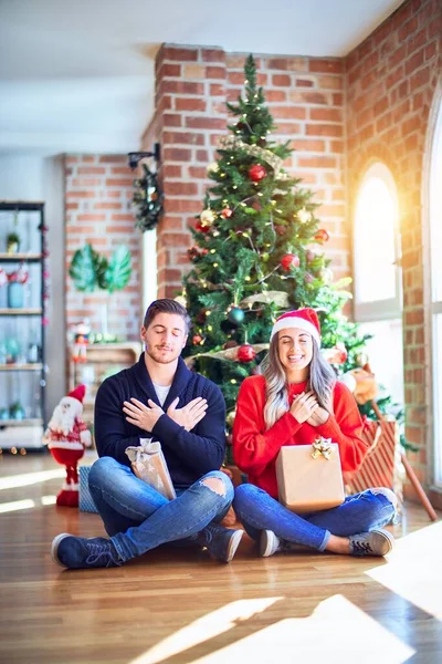 Casal Jovem Vestindo Chapéu Papai Noel Sentado Chão Torno Árvore — Fotografia de Stock