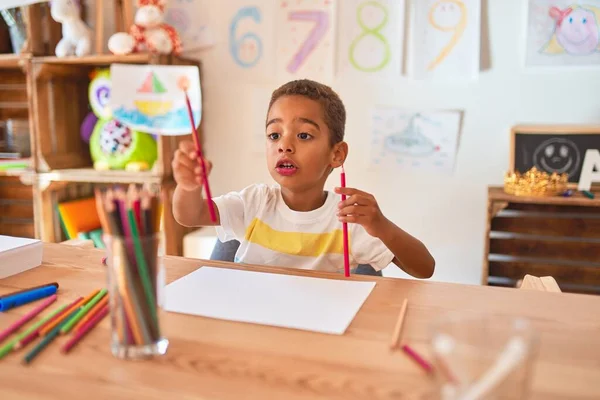 美しいアフリカ系アメリカ人の幼児は 幼稚園で机の上に紙と鉛筆を使って絵を描く — ストック写真