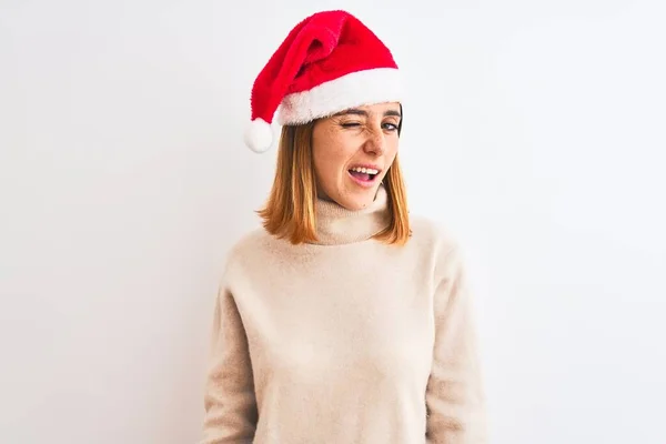 Hermosa Mujer Pelirroja Con Sombrero Navidad Sobre Fondo Aislado Guiño —  Fotos de Stock