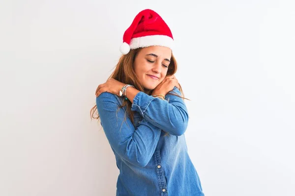 孤立した背景の上にクリスマスの帽子を身に着けている若い美しい赤毛の女性自信を持って幸せと肯定的な 笑顔を抱きます 自己愛と自己ケア — ストック写真