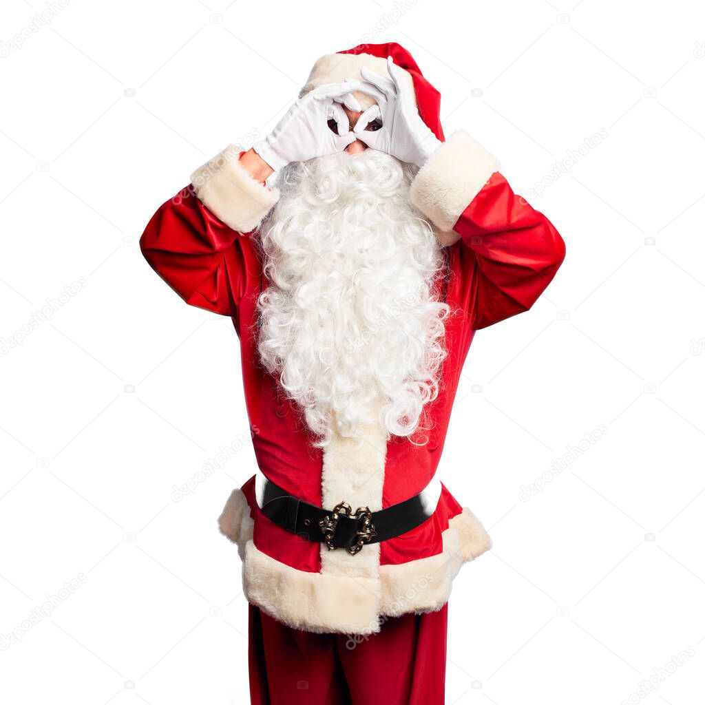 Middle age handsome man wearing Santa Claus costume and beard standing doing ok gesture like binoculars sticking tongue out, eyes looking through fingers. Crazy expression.