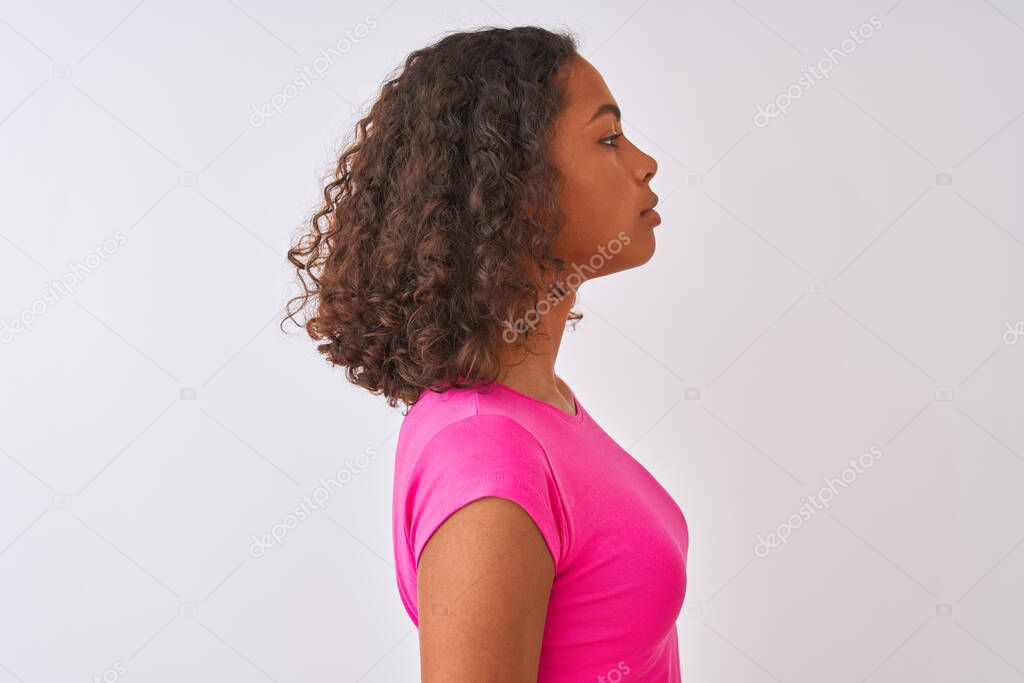 Young brazilian woman wearing pink t-shirt standing over isolated white background looking to side, relax profile pose with natural face with confident smile.