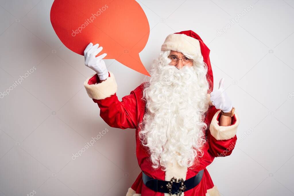 Middle age man wearing Santa costume holding speech bubble over isolated white background happy with big smile doing ok sign, thumb up with fingers, excellent sign