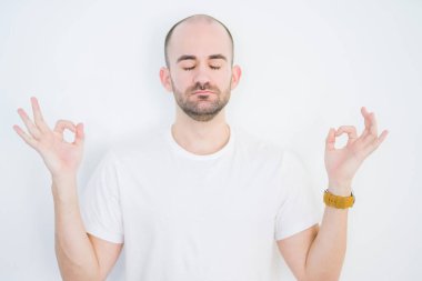 Beyazların izole edilmiş arka planında genç kel bir adam rahatla ve parmaklarıyla meditasyon hareketi yaparken gözleri kapalı gülümse. Yoga konsepti.