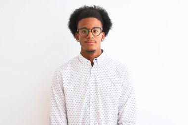 Zarif bir gömlek ve gözlük takan genç Afro-Amerikan bir adam izole edilmiş beyaz bir arka plan ve yüzünde ciddi bir ifade var. Basit ve doğal bir şekilde kameraya bakıyorsun..