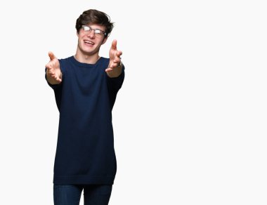 Sarılmak için kollarını açarak gülümseyerek kameraya bakarak izole arka plan üzerinde gözlük takan yakışıklı delikanlı. Neşeli ifade kucaklayan mutluluk.