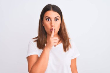 Güzel ve genç esmer bir kadının portresi izole edilmiş beyaz arka planda dikiliyor ve parmakları dudaklarında sessiz olmak istiyor. Sessizlik ve gizli konsept.