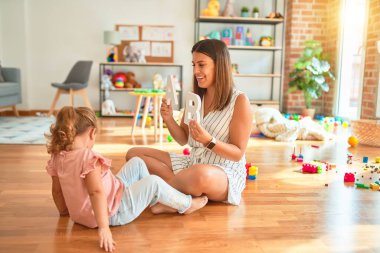 Anaokulunda sarışın bir kıza alfabe öğreten genç ve güzel bir öğretmen.