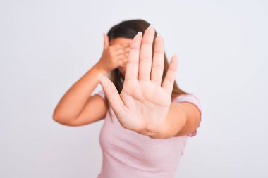 Güzel genç bir kadının portresi izole edilmiş beyaz arka planda duruyor. Gözleri ellerle kaplıyor ve üzgün ve korku dolu ifadelerle jestleri durduruyor. Utanç verici ve olumsuz bir kavram..