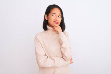 Balıkçı yaka kazak giyen genç Çinli bir kadın izole edilmiş beyaz arka planda dikiliyor. Bir soru hakkında endişeleniyor, endişeli ve gergin.