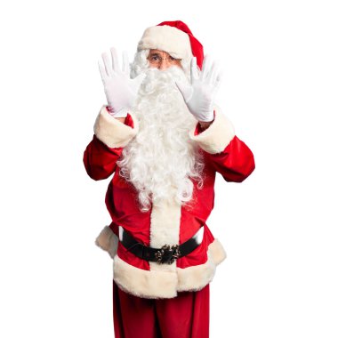 Orta yaşlı yakışıklı adam, Noel Baba kostümü ve sakal takmış, on numaralı parmaklarıyla onu gösterirken, kendinden emin ve mutlu bir şekilde gülümsüyor..