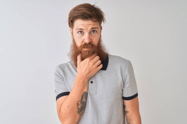 İzole edilmiş beyaz arka planda duran gri polo giyen genç kızıl saçlı adam kameraya kollarını kavuşturup gülümseyerek ve çenesini kaldırarak bakıyor. Olumlu düşünüyorum..