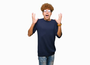 Yakışıklı delikanlı ile deli kutluyor gözlük takan ve silah ile başarı için heyecanlı çığlık kaldırdı ve açık gözleri hayret afro. Kazanan kavramı