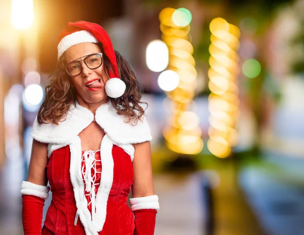 中年妇女穿着圣诞老人的服装 带着滑稽的表情高兴地伸出舌头 情感概念 — 图库照片