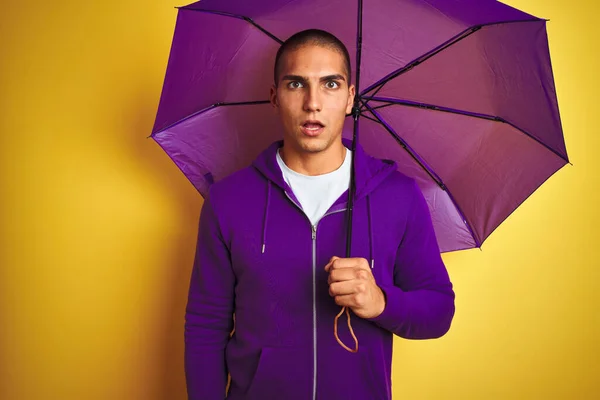 Young Handsome Man Wearing Purple Umbrella Yellow Isolated Background Scared — Stock Photo, Image
