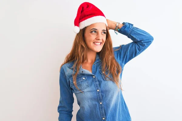 年轻美丽的红头发女子头戴圣诞帽 身披孤零零的背景 自信地微笑着 手挽着头发 显得迷人而时尚 — 图库照片