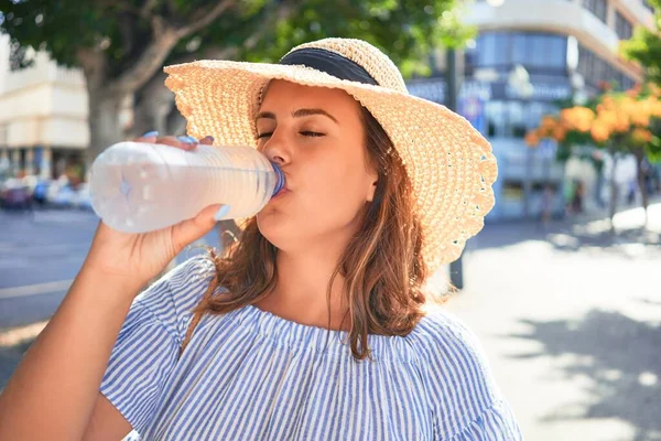 在阳光明媚的夏日 年轻美丽的女人高兴地走在城市的街道上 喝着一瓶新鲜的水 — 图库照片