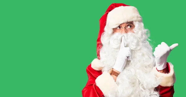 中年英俊男子身穿圣诞老人服装 留着胡子 站在那里要求安静 手指放在嘴唇上 手拉手放在旁边 沉默和秘密概念 — 图库照片