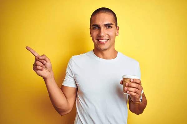 若いですハンサムな男飲みます取りますコーヒーのガラスの上に黄色隔離された背景非常に幸せなポインティングとともに手と指へ側 — ストック写真