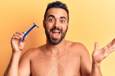 İspanyol asıllı genç adam elinde jilet tutarak başarıyı mutlu bir gülümsemeyle kutluyor ve kazanan el kaldırarak ifade ediyor. 