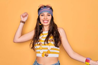 Mavi gözlü genç, güzel hippi kadın aksesuar ve güneş gözlüğü takıyor mutlu ve neşeli dans ediyor, gülümsüyor rahat ve kendinden emin bir şekilde müzik dinliyor.