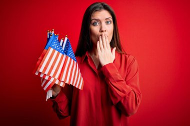 Mavi gözlü, genç, vatansever bir kadın kırmızı arka planda bayraklar tutuyor. Ağzı kapalı, utançtan ağzı açık, korkunun ifadesi, sessizlikten korkan, gizli bir konsept.