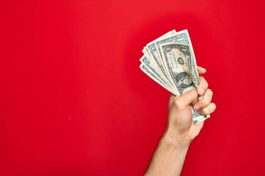 Güzel bir el, kırmızı arka planda bir deste dolar tutan bir adam.