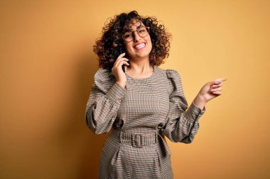 Güzel Arap iş kadını gözlüklü, akıllı telefonuyla konuşan elini ve parmağını yana uzatarak mutlu mesut konuşuyor.