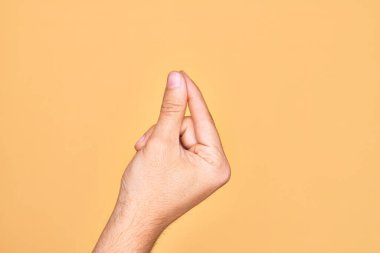 İzole edilmiş sarı arka planda parmaklarını gösteren beyaz bir adamın eli. Parmak, iş ve reklamla boş bir alan tutuyor.