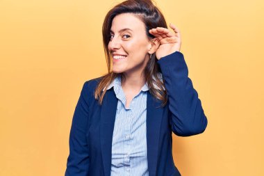 Genç ve güzel bir kadın iş kıyafetleri giyip sırıtarak kulaklarını tıkayıp dedikoduları ve dedikoduları dinliyor. Sağırlık kavramı. 