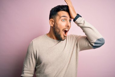 Soyutlanmış pembe arka plan üzerinde duran sıradan bir süveter giyen genç yakışıklı bir adam hata sonucu el ele tutuşarak şaşırdı. Hatayı hatırla. Unuttum, kötü hafıza konsepti.