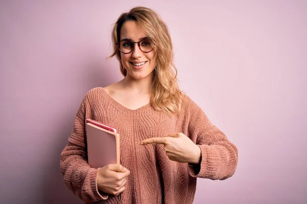 Ung Smuk Blondine Kvinde Iført Briller Holder Notesbog Lyserød Baggrund - Stock-foto