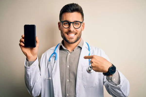 Młody Lekarz Noszący Stetoskop Pokazujący Ekran Smartfona Odizolowanym Tle Zaskakującą — Zdjęcie stockowe