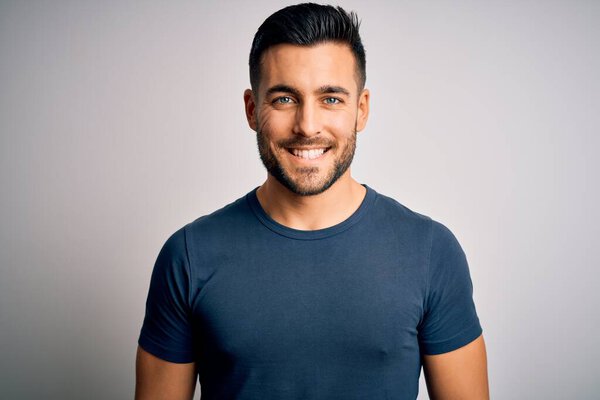 Young handsome man wearing casual t-shirt standing over isolated white background with a happy and cool smile on face. Lucky person.