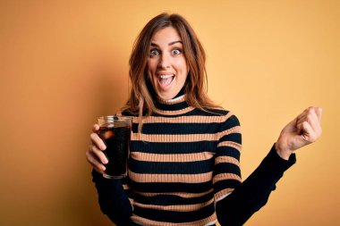 Genç, güzel esmer kadın kola ile bardak içiyor saman kullanarak gururla bağırıyor ve zaferi ve başarıyı kutluyor çok heyecanlı, coşkulu bir duygu.